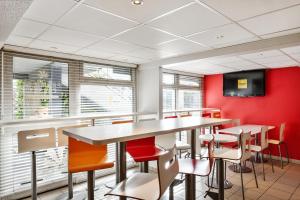a restaurant with red walls and tables and chairs at Premiere Classe Vannes in Vannes
