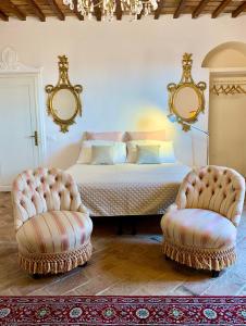 ein Schlafzimmer mit einem Bett und zwei Stühlen in der Unterkunft Casa Cerboneschi B&B in a medieval village with Panoramic Tuscan Hills in Casale Marittimo