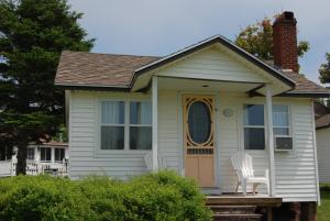 a white house with a white chair on the porch at Shining Waters - Ingleside Cottages in Cavendish