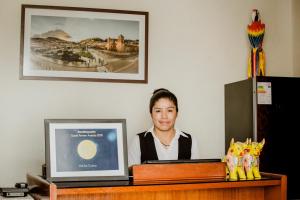 une femme assise sur un bureau avec un ordinateur dans l'établissement Askha Cusco, à Cusco