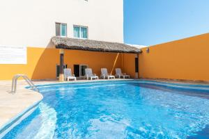 ein Schwimmbad mit Stühlen und ein Gebäude in der Unterkunft Hotel Gran Via Veracruz in Veracruz