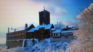 un edificio cubierto de nieve con una torre de reloj en Schöne Aussicht, Wallbox, 70qm, kontaktloser Check-in, en Eisenach
