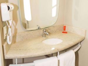 un bagno con lavandino e specchio di Ibis Lorena - Circuito da Fé a Lorena