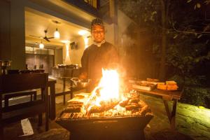 a man standing in front of a grill with food at Forest Shade Eco Resort in Deraniyagala