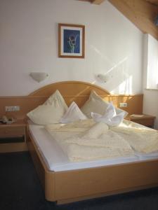 a wooden bed with white sheets and pillows at Hotel Haselried in Tirolo