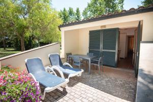 patio z niebieskimi krzesłami i stołem oraz dom w obiekcie Ghiacci Vecchi Residence w mieście Venturina Terme