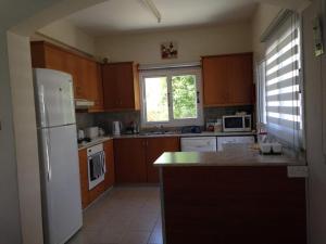 a kitchen with wooden cabinets and a white refrigerator at Villa Laurel in Peyia