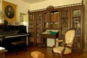 een kamer met een piano, een bureau en boekenplanken bij Pazo Cibrán in San Xulián de Sales