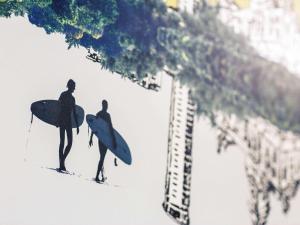 two surfers walking down the beach with their surfboards at Mercure Swansea Hotel in Swansea