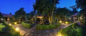 une maison avec un jardin éclairé la nuit dans l'établissement Aranyak Resort, à Tāla