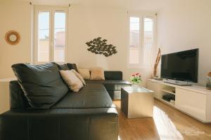 sala de estar con sofá de cuero negro y TV de pantalla plana en Le Cleli en Cassis