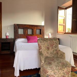a bedroom with a bed with a pink pillow and a chair at Casa Cuco in Serdio