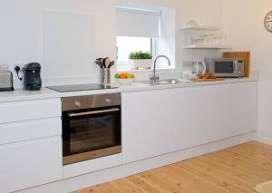 a white kitchen with a sink and a stove at Hillside Studio in Penzance