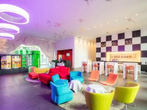 un vestíbulo con sillas y mesas coloridas y un bar en ibis Styles Basel City, en Basilea