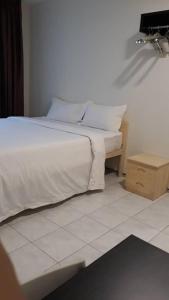 - un lit avec des draps et des oreillers blancs dans l'établissement Mjc New township 6BR by Natol Homestay-MJC, à Kuching