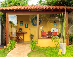 a yellow house with a patio with red chairs at Pousada Jardim da Nova Era in Alto Paraíso de Goiás