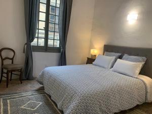 um quarto com uma cama com almofadas brancas e uma janela em COSY CENTRE HISTORIQUE em Arles