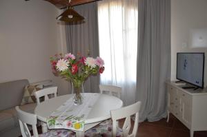 una mesa de comedor blanca con un jarrón de flores. en Il Cuoricino Podere le Bozze con piscina, WI-FI, posto auto, en Castagneto Carducci