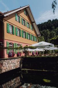 ein Gebäude mit grünen und rosa Fenstern und Sonnenschirmen in der Unterkunft Hotel Zur alten Mühle in Neuenbürg