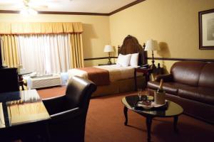 a hotel room with a bed and a couch and a table at Folk Inn Ontario Airport in Ontario