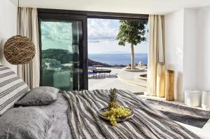 エリアビーチにあるMyconian Panoptis Escape, a member of Small Luxury Hotels of the Worldの景色を望む客室のベッドの上にフルーツを1杯用意しています。
