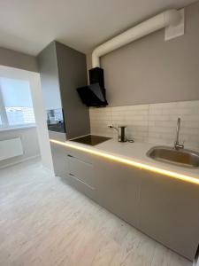 uma cozinha com um lavatório e um balcão com luzes em Свежая и красивая квартира! em Cherkasy