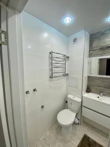 a white bathroom with a toilet and a bath tub at Свежая и красивая квартира! in Cherkasy