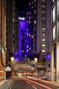 uma rua da cidade com um edifício com luzes roxas em St Giles London – A St Giles Hotel em Londres