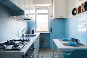 een keuken met blauwe tegels, een fornuis en een wastafel bij Fly by Suites Pescara in Pescara