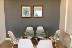 uma sala de jantar com uma mesa de vidro e cadeiras brancas em 1° B #LosPinosFrenteAlMar em Pinamar