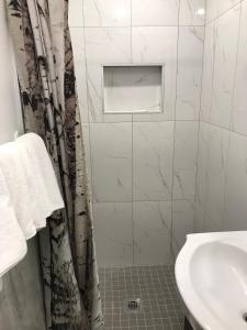 a white bathroom with a shower and a sink at Hotel La Residence du Voyageur in Montréal