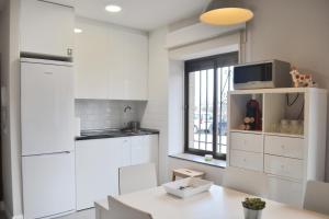 a white kitchen with white cabinets and a window at Apartamento El Monasterio in Toledo