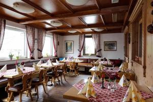 a restaurant with wooden tables and chairs and windows at Gasthof / Pension Götzfried in Tegernheim