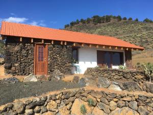 una pequeña casa de piedra con techo naranja en Casa Rural Los Santillos, en El Pinar de El Hierro