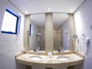 a bathroom with two sinks and a large mirror at Nobile Suites Gran Lumni in Rio Branco