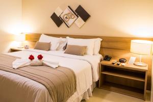 a bedroom with a large bed with two red roses on it at Nobile Suites Gran Lumni in Rio Branco