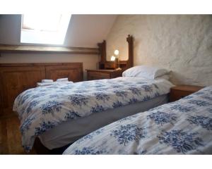 a bedroom with two beds with blue and white sheets at Tyncellar Farm holiday cottages in Margam