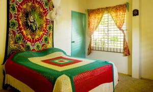 um quarto com um cobertor colorido numa cama em Zion Country em Manchioneal