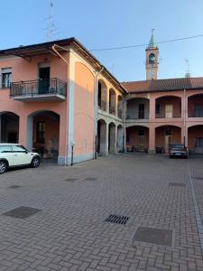 a building with a clock tower and cars parked in a parking lot at Appartamento “La Corte” in Paderno Dugnano