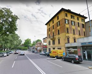 a city street with cars parked in front of a yellow building at A casa di Nat in Modena