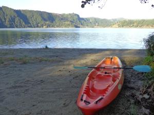 a red kayak sitting on the shore of a lake at Casa Dos Barcos Furnas in Furnas