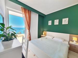 Dormitorio verde con cama y ventana en Allure Apartment, en Sarandë