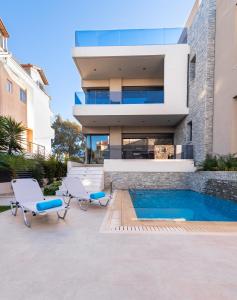 a house with a swimming pool and two chairs at Ixia Breeze 1 in Ixia
