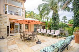 a patio with a table and chairs and an umbrella at Mac Atini Guest House in Mbabane