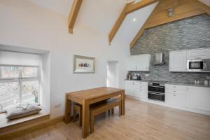 a kitchen with white cabinets and a wooden table at The Armoury in Glenfinnan