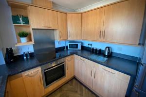 a kitchen with wooden cabinets and a black counter top at Appleby Darlington Two in Darlington