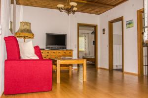 ein Wohnzimmer mit einem roten Stuhl und einem Tisch in der Unterkunft Ferienwohnung Keseberg in Lienz