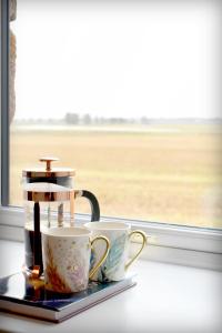 une cafetière et deux tasses assises sur un rebord de fenêtre dans l'établissement The Auld Reekie, à Barbaraville