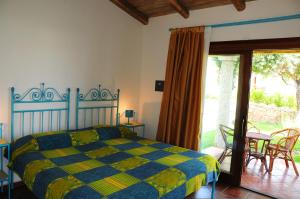 a bedroom with a blue and yellow bed and a patio at Le Tre Querce in San Teodoro