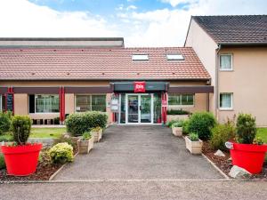 un edificio con macetas rojas delante de él en ibis Avallon, en Magny